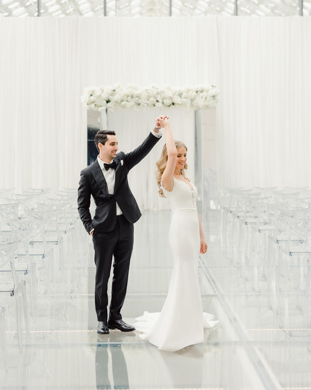 A young couple twirling in a beautiful white ballroom